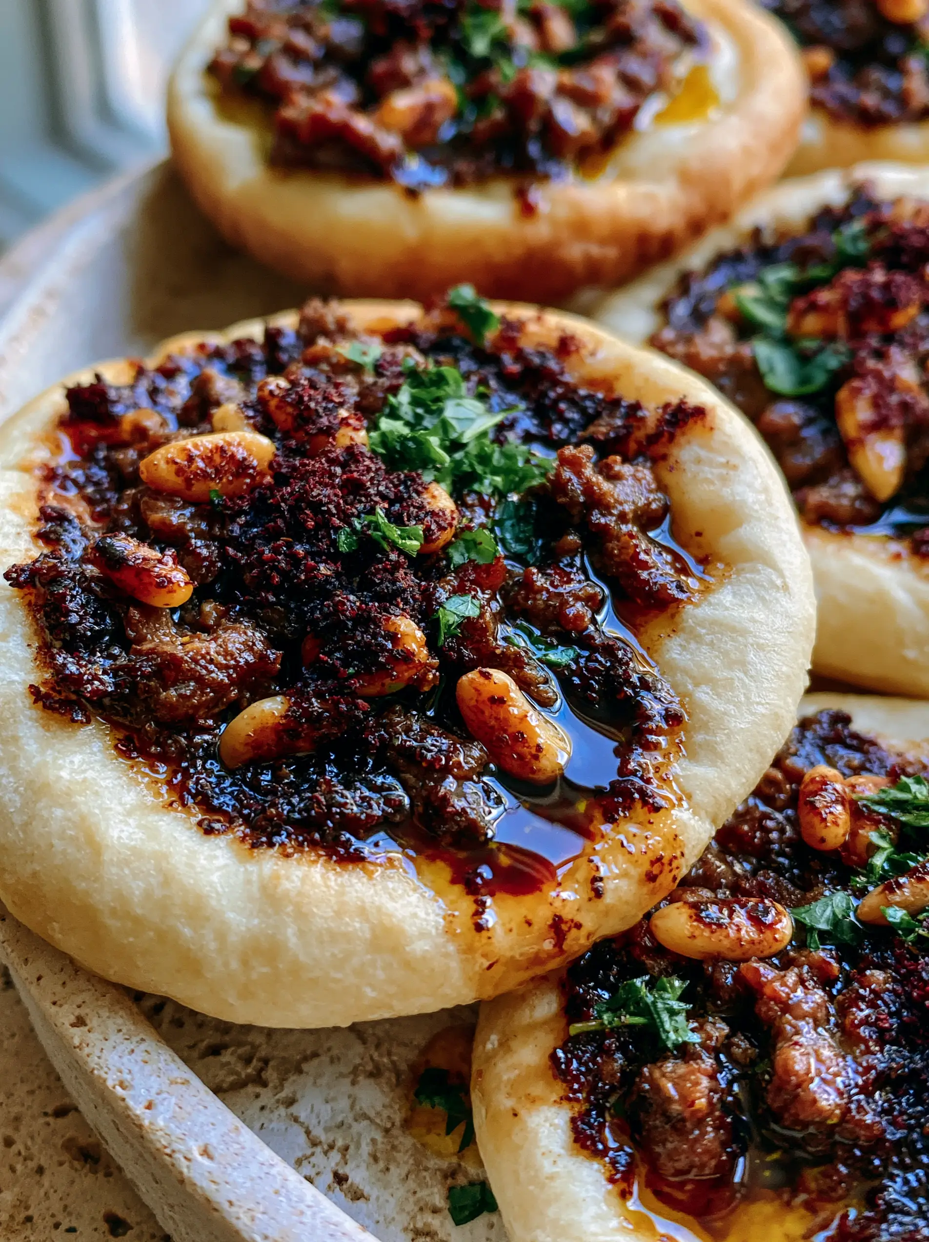 Extreme macro close-up of Lebanese meat pies showing the texture of toasted pine nuts and sumac. (Lebanese meat pies)