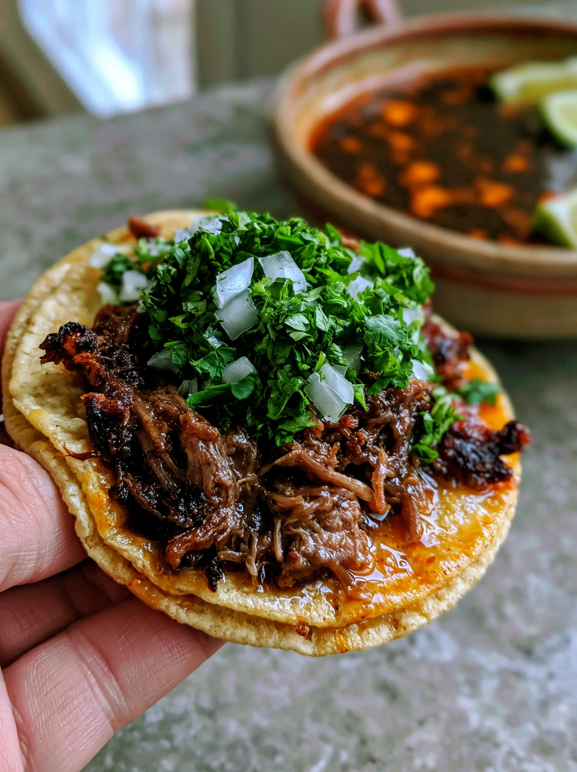 A close-up shot of an overstuffed shredded beef taco featuring glistening orange tortillas and charred meat edges. (shredded beef tacos)