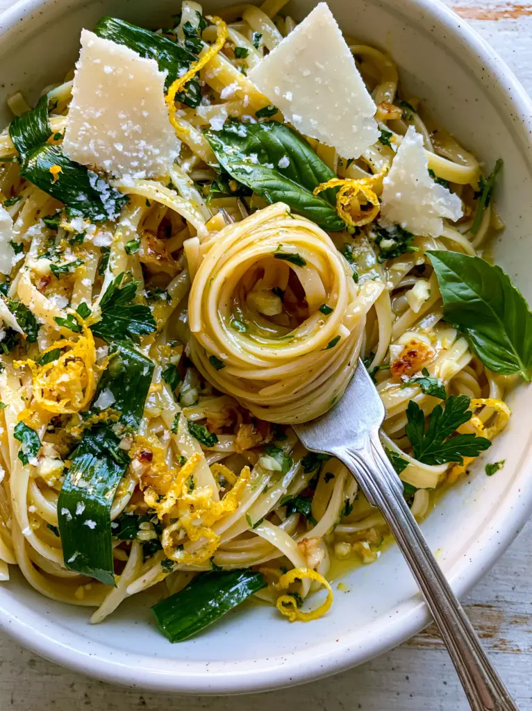 A silver fork lifting a nest of linguine from a rustic white bowl, showing the silky texture of the summer pasta sauce.
