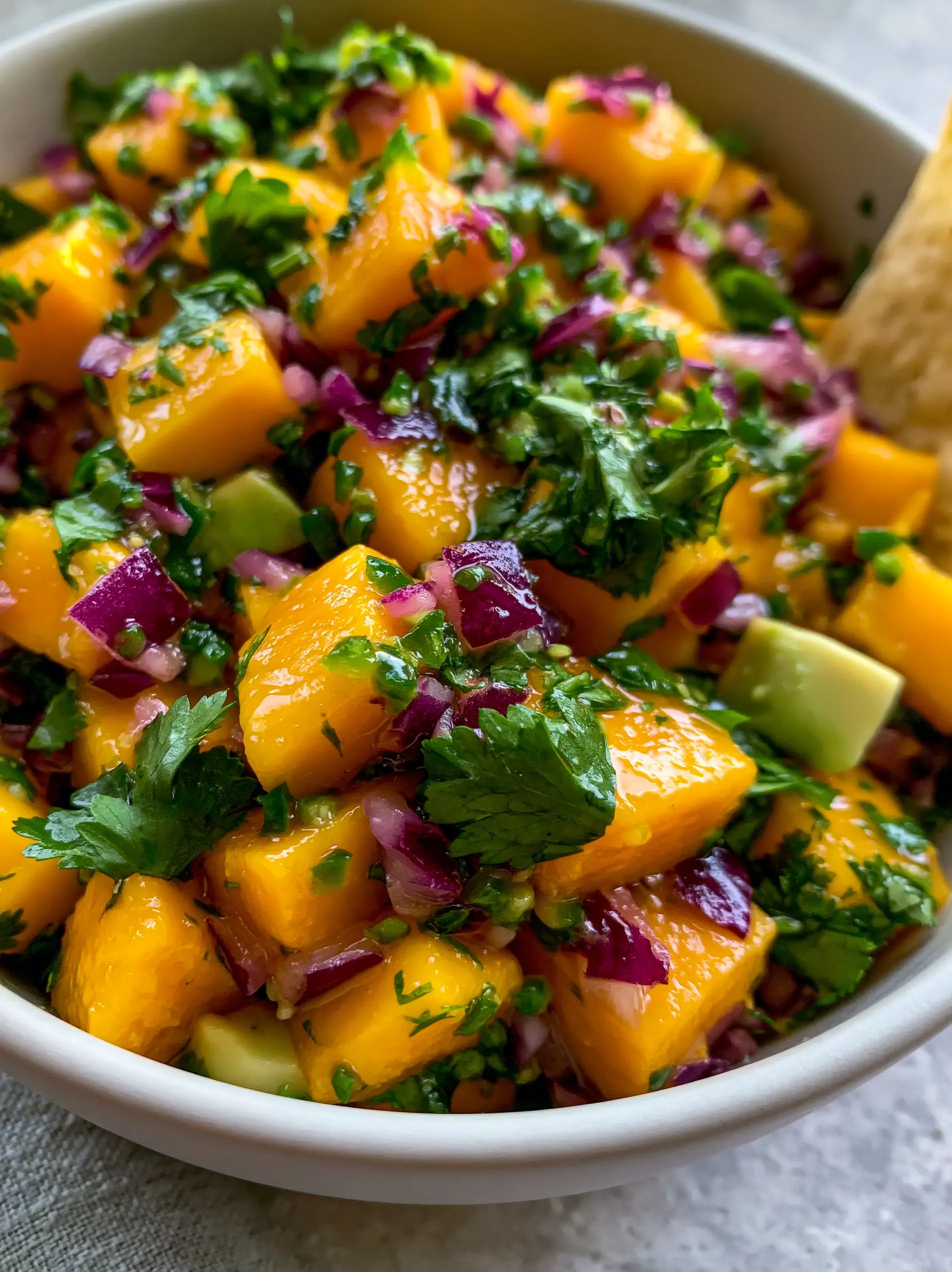 Extreme top-down view of a Mango Salsa Recipe in a white bowl featuring glistening mango cubes and fresh cilantro.
