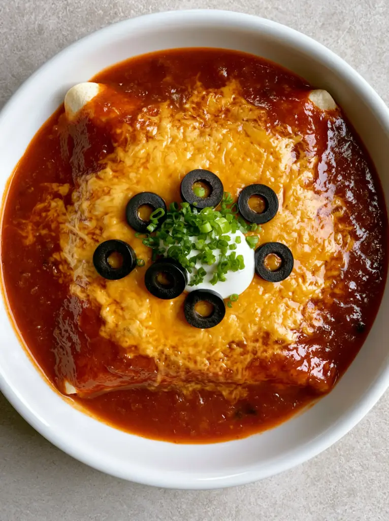 Close-up of melted cheddar cheese and glossy red sauce on a homemade Enchirito.